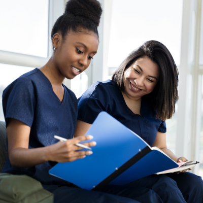 Two female advanced practice providers looking at notebook