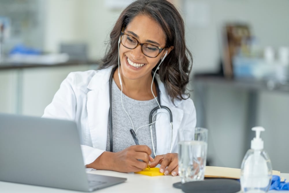 Nurse practitioner on laptop smiling and taking notes