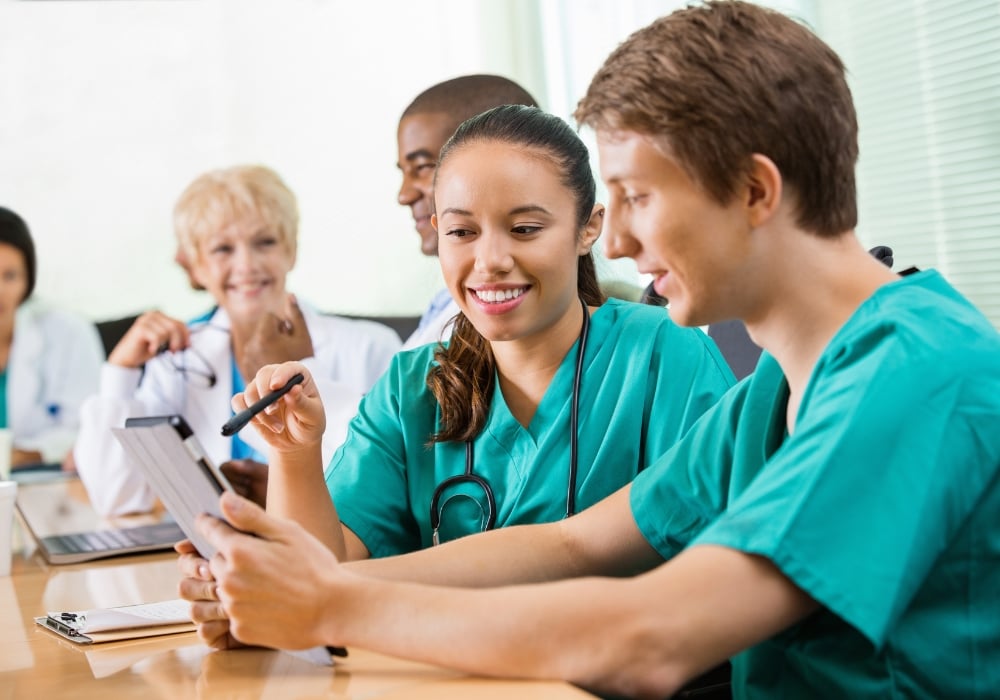 Male and female nurse practitioners looking at tablet