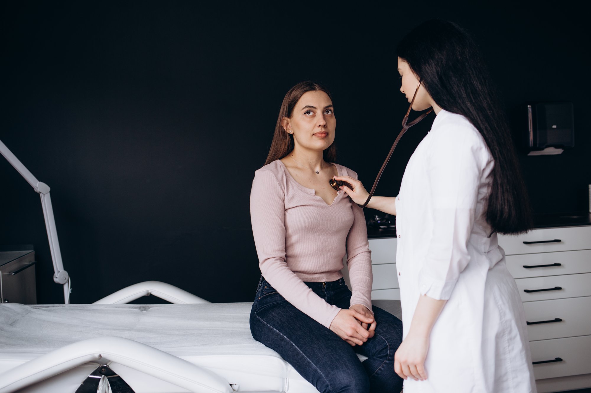 a female medical professional using a stethoscope on a female patient